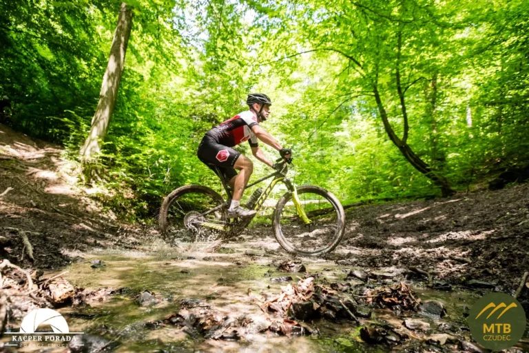 Zawodnik MTB przejeżdża przez leśny potok